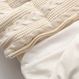 Detail view of cream cable knit texture and smooth zipper on this autumn jacket