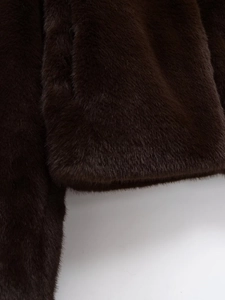 Gros plan sur la texture pelucheuse et les coutures de la veste en fausse fourrure marron