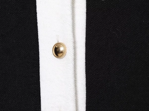 Détail d'un bouton doré sur tissu noir avec passepoil contrasté blanc élégant
