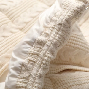 Close-up of white cable knit cardigan with smooth inner lining and premium metal zipper detail