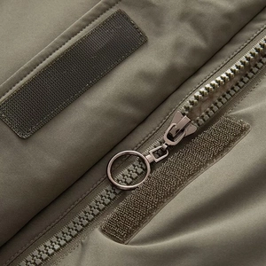 Dettaglio del parka verde militare con cerniera in resina e chiusure in velcro sul tessuto