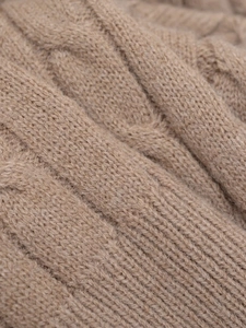 Macro shot of cable knit texture on camel brown sweater with detailed wool fibers