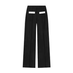 Détail d'un pantalon large noir avec des rabats de poches décoratifs blancs au dos