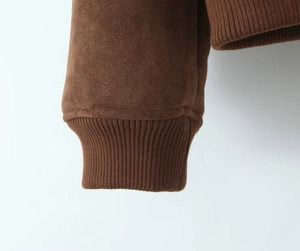 Gros plan sur la texture en daim marron foncé et les poignets en maille de la veste