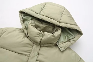 Detail of light green hooded puffer jacket featuring high neck and drawstring toggles