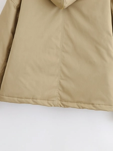 Detalle de chaqueta caqui con capucha, cremallera de metal dorado y tela cortavientos