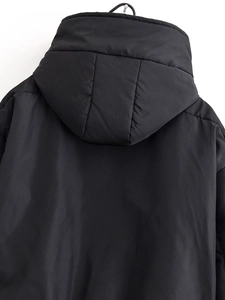 Détail de la capuche rembourrée et du tissu coupe-vent noir mat sur la veste à capuche