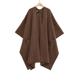 Détail de la texture du pull poncho en tricot marron foncé et des doubles poches