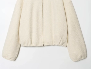 Detail showing the heavy sherpa fleece fabric and zip closure on the cream jacket
