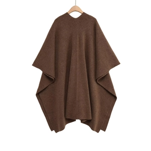Détail d'un poncho en maille marron foncé montrant le tissu épais et les finitions