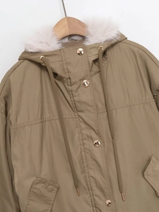 Detail of khaki parka jacket featuring a plush faux fur hood and golden snap buttons