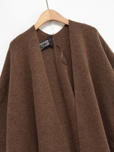 Détail de la texture d'une cape en tricot marron avec poches et tissu en laine doux