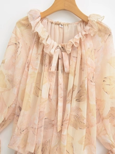 Detailed close-up of light chiffon floral shirt with ruffle collar and ribbon tie-up detail