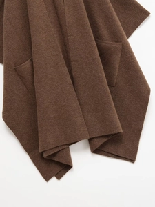 Détail macro de la maille marron foncé et de la poche de ce poncho d'hiver chic