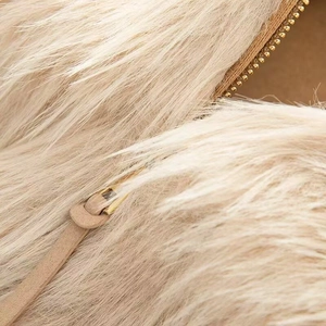 Detail of high-quality golden zipper on soft off-white faux fur texture of a jacket