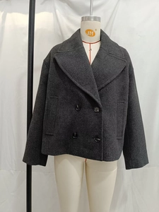 Dettaglio della spessa trama effetto lana e dei bottoni su un cappotto grigio scuro