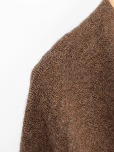 Détail de la texture en maille marron foncé et du tissu en laine douce sur un cintre