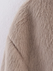 Close-up of soft light camel faux fur texture on long sleeve single-breasted coat