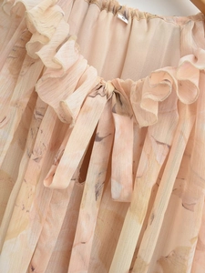 Detail of ruffled elastic neckline with a bow on lightweight floral chiffon fabric