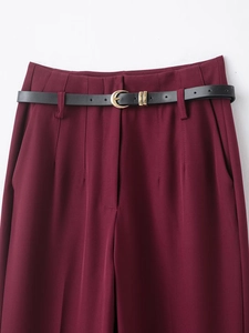 Détail d'un pantalon taille haute bordeaux avec une fine ceinture noire et boucle