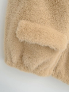 Détail de la poche de la veste en fausse fourrure camel montrant la texture douce