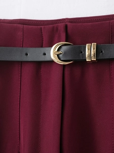 Gros plan du pantalon bordeaux avec ceinture en cuir noir et boucle en C dorée élégante