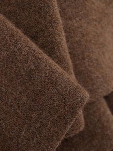 Gros plan de la texture du tricot marron foncé sur le manteau cape élégant de mi-longueur