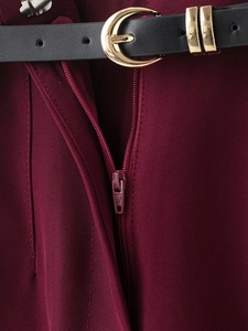 Vue détaillée du pantalon bordeaux avec ceinture noire et boucle demi-cercle dorée élégante