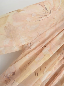 Detail of light apricot floral chiffon dress showing micro-pleated texture and soft prints