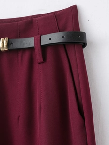 Gros plan d'un pantalon bordeaux avec ceinture noire et boucle carrée dorée élégante