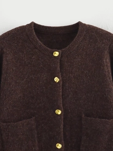 Détail d'un cardigan en maille marron foncé avec boutons dorés et texture de poche