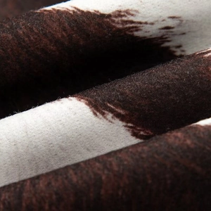 Macro shot of soft faux fur jacket fabric with brown and white cow print texture
