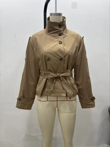 Detail of khaki double-breasted trench coat featuring a stand collar and waist tie belt