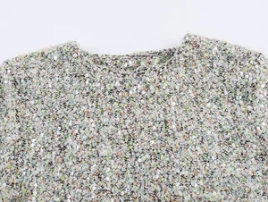 Détail du tissu en maille multicolore avec paillettes argentées sur le haut à manches