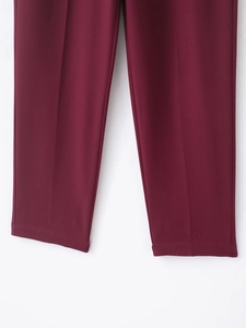 Détail d'un pantalon bordeaux à jambe droite avec pli central et ourlet invisible fin