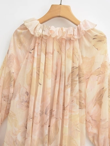 Detail of floral chiffon top with ruffle neckline and vertical pleats in apricot