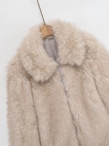 Detail of soft cream faux fur texture and zipper closure on a wide collar jacket