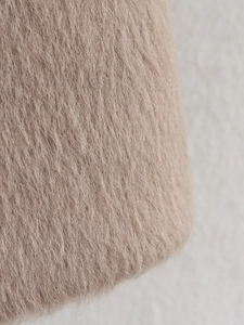 Close-up of soft beige faux fur texture showing thick plush fibers on stylish coat