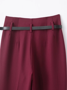 Détail du pantalon bordeaux taille haute avec ceinture noire et plis élégants