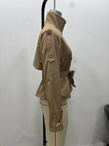 Detail of khaki trench jacket featuring buttoned epaulettes and adjustable cuff straps