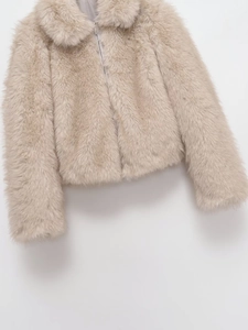Detailed macro view of the silver metal zipper on soft beige faux fur jacket