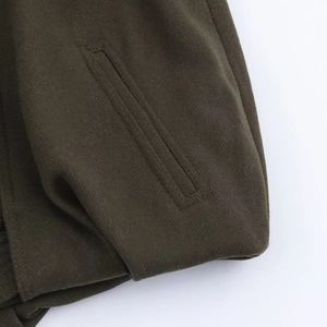 Detailed close-up of a straight welt pocket on a dark olive green wool baseball jacket
