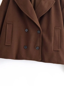 Dettaglio del cappotto di lana marrone scuro con bottoni doppiopetto e colletto a rever