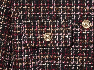 Close-up of pink tweed jacket fabric showing gold metal buttons and a flap pocket detail