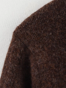 Gros plan détaillé sur la texture en maille peluche marron et la couture d'épaule soignée