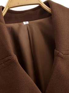 Dettaglio del risvolto del cappotto di lana marrone e etichetta taglia S