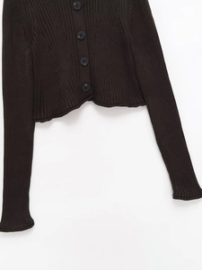 Détail du cardigan noir en maille côtelée avec boutons et finitions à bords ondulés