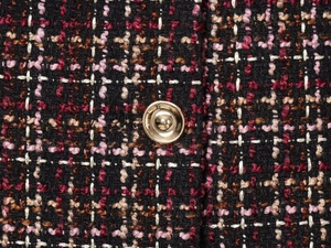 Close-up of multicolored tweed fabric with gold metallic thread and a round metal button