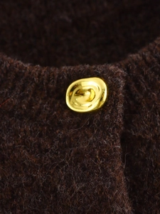 Gros plan d'un bouton doré sur un tricot marron foncé avec une texture douce et veloutée