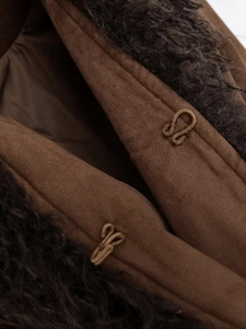 Close-up of woven hook-and-eye closures on a dark brown faux suede and fur jacket